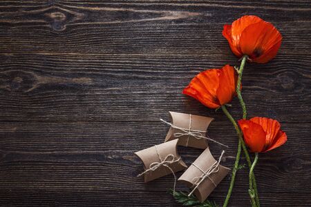 Red poppies flowers with gift boxes on dark wood background. Top view with copy space.の写真素材