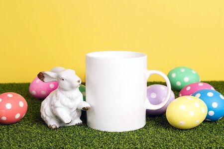 White coffee mug with Easter decoration on a green grass background. Space for text or design.の写真素材