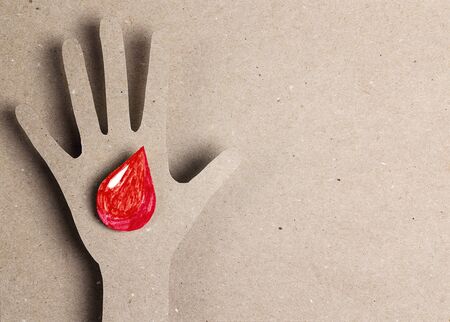 Hand symbol with a drop of blood on a cardboard background with copy space. World Hemophilia or...