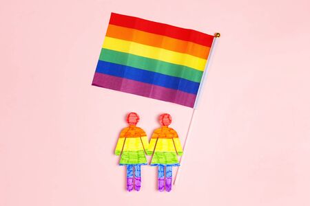 Lesbian couple figures holding hands with rainbow flag on pink background. LGBT pride.の写真素材