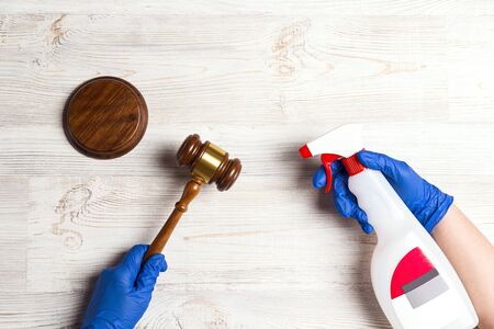 Hands in medical gloves treated with a sanitizer judge's hammer. Judicial system and law during the coronavirus.の写真素材