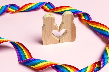 LGBT couple wooden figures with rainbow ribbon. Pride tape symbol. Gender equality concept.の写真素材