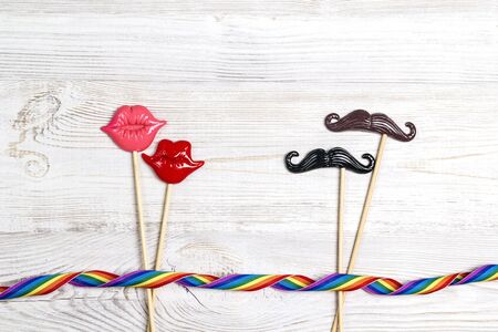 Pair of decorative lips and mustache with rainbow ribbon on wooden background. LGBT pride.の写真素材