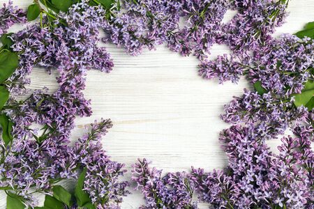 Frame of lilac flowers on light wooden background. Top view, flat lay, copy space. Spring flowers.の写真素材