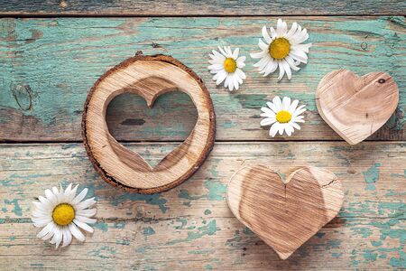 Wooden hearts with daisies on old turquoise wooden background. Top view.の写真素材
