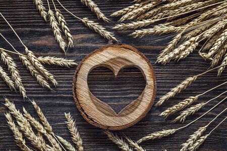Background with ears of wheat and wooden heart on dark wooden boards. Space for text. Top viewの写真素材