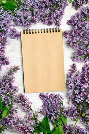 Open blank notepad with lilac flowers on wooden table. Top view, flat lay, copy space.の写真素材
