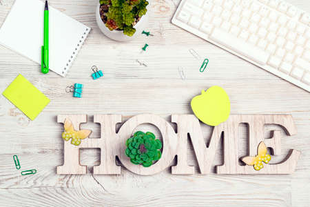 Work home concept. Office desk table with computer keyboard, paper notepad, pen, supplies and green plant on light wood background. Top view, flat lay workspace. Work, freelance or education concept.の写真素材