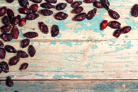 Dry rose hips on wooden table with copy space. Folk medicine plants.