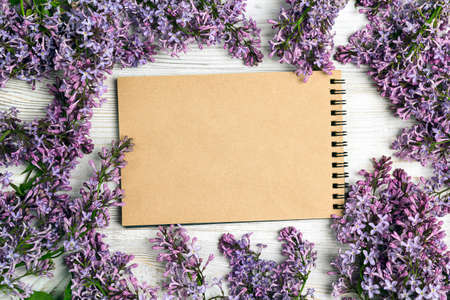 Open blank notepad with lilac flowers on wooden table. Top view, flat lay, copy space.の写真素材