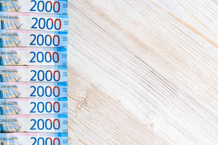 Border of Russian money banknotes currency rouble in nominal value of two thousand on wooden table....