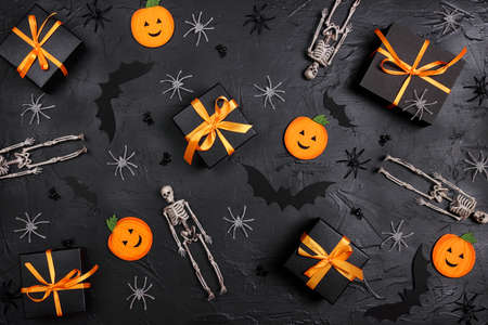 Halloween holiday background with gifts and decorations on black backdrop. Festive set with funny pumpkins, bats, skeletons and spiders.の写真素材