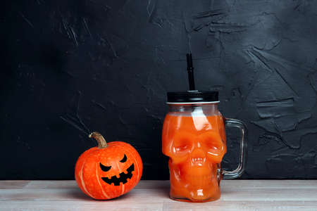Orange Halloween cocktail in skull glass jars with pumpkin head Jack lantern on black background. Copy space for text.の写真素材