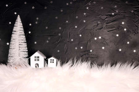 Christmas and New Year miniature house with fir trees and snowfall on blue background. Copy space for text. Winter card. Holiday and celebration concept.の写真素材