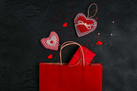 Red shopping bag with gift and hearts on black background. St. Valentines Day shopping and discounts concept.の写真素材