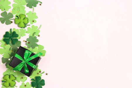 Black gift box with green ribbon and clover leaves on white background. Lucky shamrock, St....