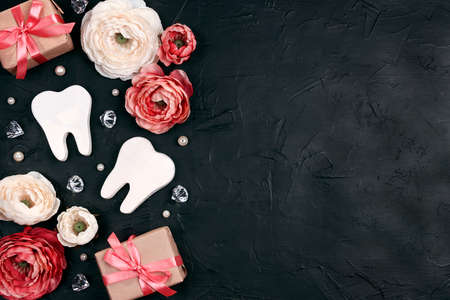 Festive dental background with teeth, flowers, gifts and crystals on a black background with copy...
