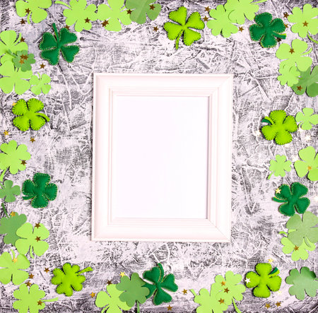 Saint Patrick's Day concept. White frame with decorative clover leaves on gray background. Top down flat lay composition with copy space.の写真素材