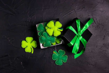 Gift boxes with lucky clover leaves on black background. Saint Patrick's Day concept. Top down flat lay composition.の写真素材
