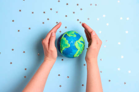 Female hands protect the planet among the stars on a blue background. Earth Day, ecology and nature protect.の写真素材