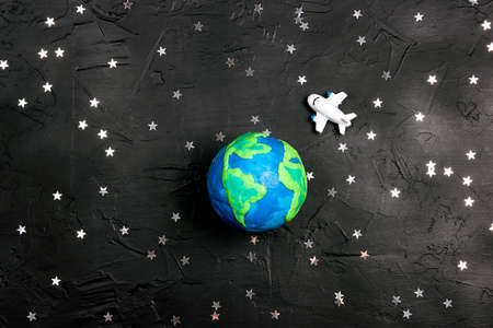Plane is flying through the world over the Earth globe among the stars on a black background. Tourism, travel concept.の写真素材
