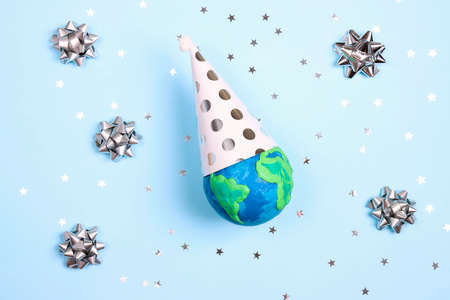 Planet Earth with party cap, bows and stars on a blue background. Ecology, environmental protection. World Earth Day concept.の写真素材
