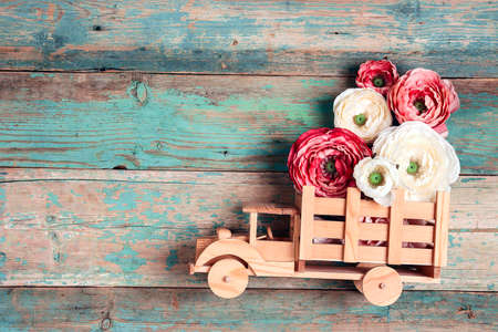 Wooden toy truck with peonies flowers in the back on shabby wooden turquoise boards. Space for text. Festive greeting card.の写真素材