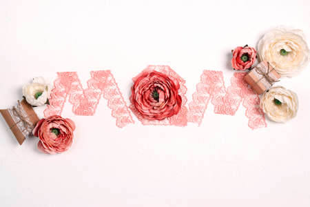Lace word MOM with peony flowers and gifts on white background. Mother's Day greeting card.の写真素材