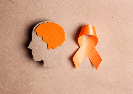 World Multiple Sclerosis Day. Orange awareness ribbon and brain symbol on a brown background.の写真素材