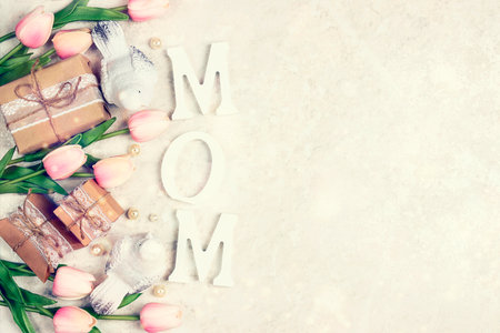 Festive border from tulip flowers, gifts and birds with word MOM on light marble. Mother's Day greeting card.の写真素材