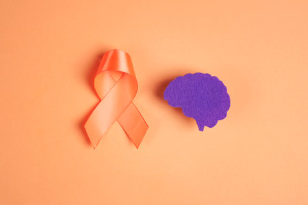 World Multiple Sclerosis Day. Orange awareness ribbon and violet brain symbol on a orange background.の写真素材