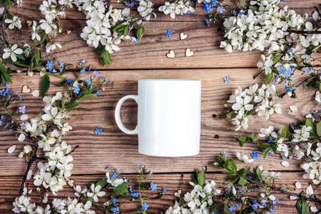 White coffee mug with apple blossom and forget-me-nots on old wooden boards. Space for text or...