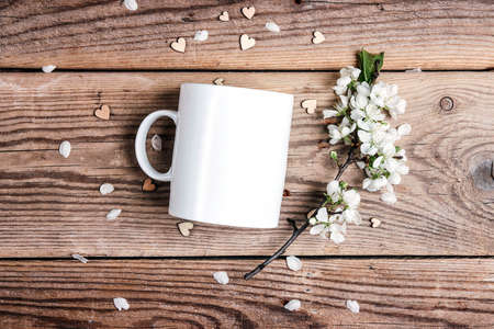 White coffee mug with apple blossom branch on old wooden boards. Space for text or design.の写真素材