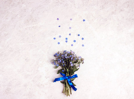 Small bouquet of forget-me-nots on a light marble background. Top view with copy space for text.の写真素材