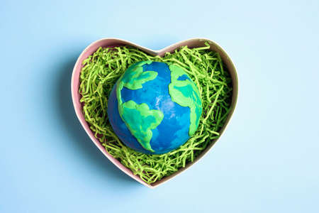 Planet in a heart gift box on a blue background. Earth Day, ecology and nature protect.