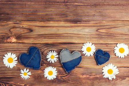 Daisies with denim hearts on wooden background. Top view, copy space for text.の写真素材