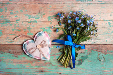 Small bouquet of forget-me-nots with heart on shabby turquoise wooden background.の写真素材