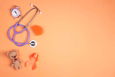 World Multiple Sclerosis Day. Orange awareness ribbon, brain symbol, toy bear and alarm clock on a orange background.の写真素材