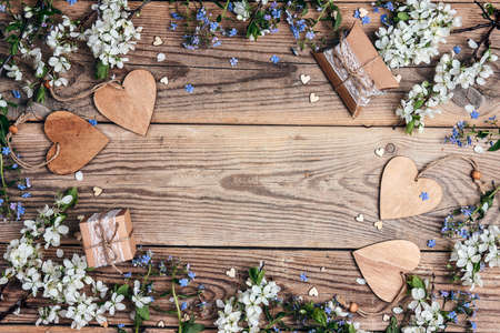 Romantic background with apple blossom, gifts and hearts on old wooden boards. Top view with copy...