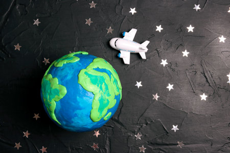 Plane is flying through the world over the Earth globe among the stars on a black background. Tourism, travel concept.の写真素材