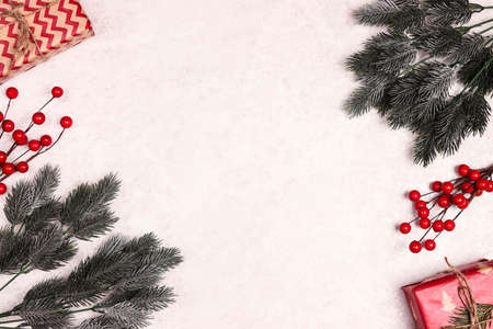 Christmas frame of gifts, spruce branches and berries on light marble background. Christmas, winter,...
