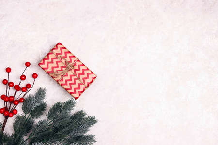 Christmas border of gift, spruce branches and berries on light marble background. Christmas, winter,...