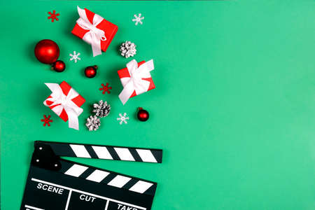 Movie clapper board with Christmas decorations and gifts on a green background with copy space. Cinema for the winter holidays.の写真素材
