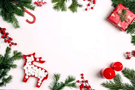 Frame from holiday decorations, spruce branches and sweets on white background. Space for text, top...