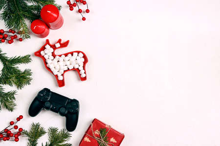 Joystick gaming controller with gift, fir brabches, red berries and marshmallows on white...