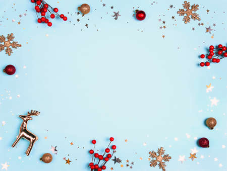 Festive blue background with gold and red decorations and berries. Christmas, winter, new year frame with copy space.の写真素材