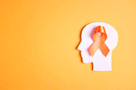 World Multiple Sclerosis Day. Orange awareness ribbon and brain symbol on a yellow background. Copy space for text.の写真素材