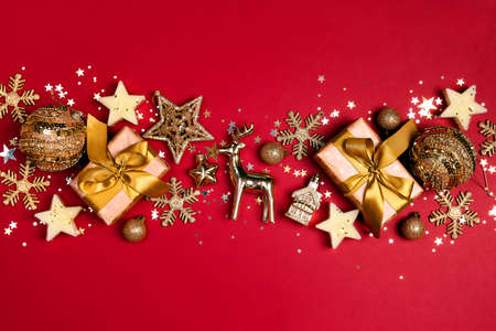 Gold Christmas composition made of gifts and shiny decorations on a red background. Copy space, top view.の写真素材