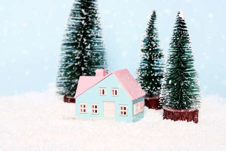 Toy snowy landscape with a small house surrounded by fir trees. Winter card. Holiday and celebration concept.の写真素材