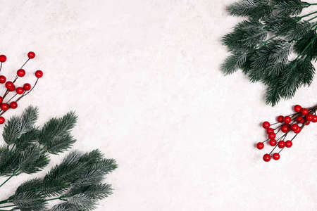 Christmas frame of spruce branches and red berries on light marble background. Christmas, winter, new year concept.の写真素材